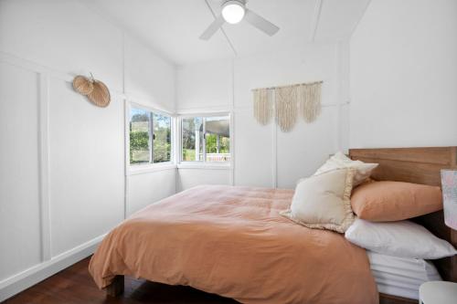 a bedroom with a bed with white walls and a window at Casa Del Waters in Wooli