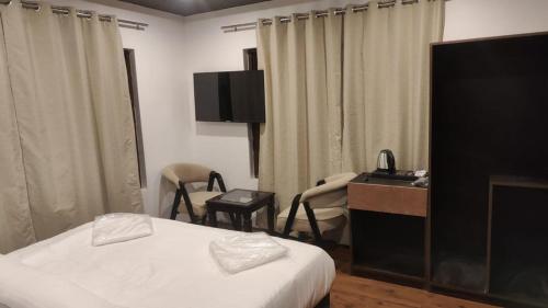 um quarto de hotel com uma cama e uma secretária com cadeiras em SKY HILLS RESORT em Pahalgām