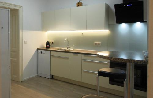 uma cozinha com armários brancos, um lavatório e uma mesa em Casa Nostra - Schöne 3-Zimmerwohnung am Augarten em Viena