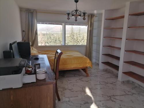 1 dormitorio con cama, ventana y escritorio en Maison de campagne à 20mn du centre ville Tunis en Mornag