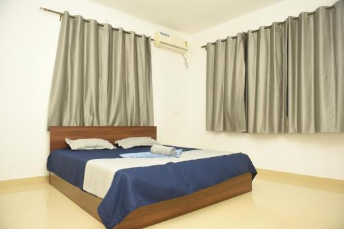 Sai Homestay Panaji 2 BHK and Studio Apartment في باناجي: غرفة نوم بسرير وملاءات زرقاء وستائر