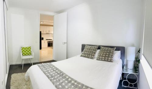 een witte slaapkamer met een groot bed en een stoel bij D101 Charming Apartment- Free Parking in Melbourne
