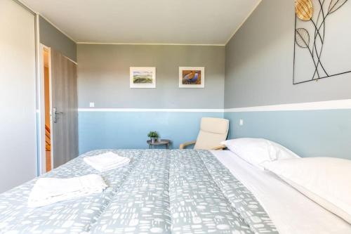 a bedroom with a large white bed and a chair at Maison 12 Couchages tout confort - 11B Vialle St Gene in Saint-Genès-Champanelle