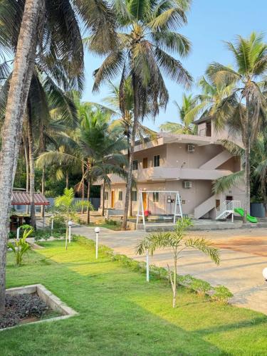 a building with palm trees in front of it at The Saltwater Home stay in Udupi