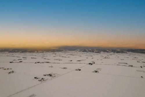 an aerial view of a snow covered field with mountains at THE CELESTIAL in Nakafurano