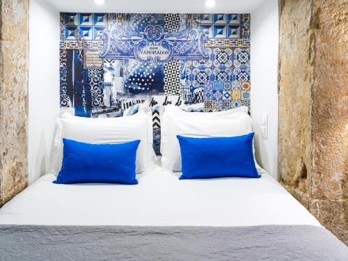 a bed with blue and white pillows and a wall at The ART INN Lisbon in Lisbon