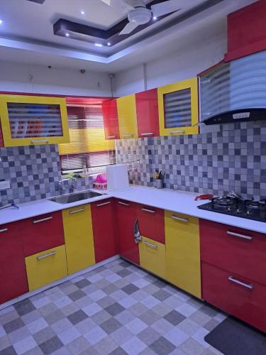 une cuisine avec des armoires rouges et jaunes et une cuisinière dans l'établissement Galeela apartment Cochin, à Cochin