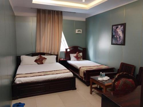 ein Hotelzimmer mit 2 Betten und einem Tisch in der Unterkunft Nhat Quy Hotel in Tây Ninh