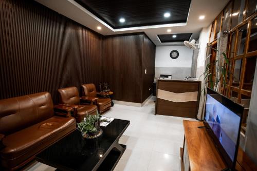 a living room with leather furniture and a tv at 2K HOTEL in Kohīma