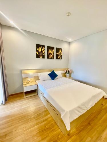 - une chambre avec un grand lit blanc et du parquet dans l'établissement Homestay Hạ Long, à Hạ Long