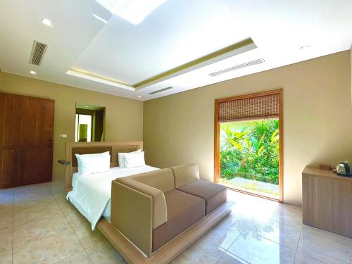 a bedroom with a bed and a couch and a window at BaHo Eco Beat in Ninh Hòa