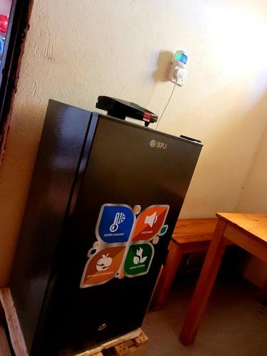 a black refrigerator with stickers on it next to a table at Welcominghome in Ishaka