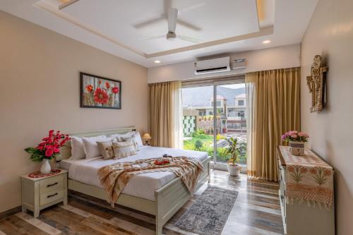 um quarto com uma cama e uma grande janela em Alaya Heaven in Hills Luxe 2BHK Villa with Pvt Pool, Udaipur em Udaipur