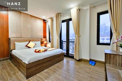 um quarto com uma cama e uma varanda com janelas em HANZ Gia Hoang Hotel em Da Lat