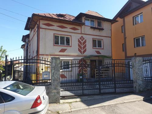 um carro branco estacionado em frente a uma casa com um portão em Apartament Mansarda Venus em Râmnicu Vâlcea