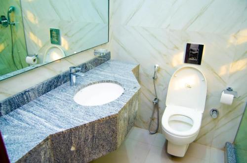 a bathroom with a toilet and a sink with a mirror at Luxury Oasis 1 - Entire 1 Bedroom Apartment in Abuja with Pool, Games, WiFi, Balcony, and Garden in Abuja
