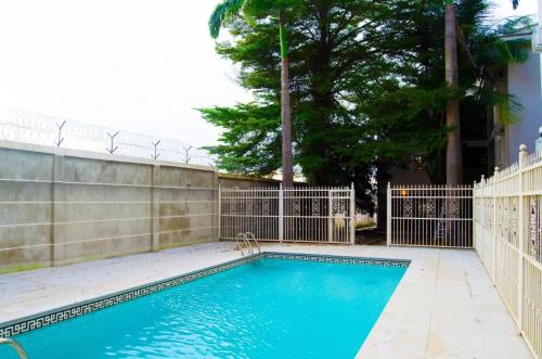 a swimming pool in front of a fence at Luxury Oasis 1 - Entire 1 Bedroom Apartment in Abuja with Pool, Games, WiFi, Balcony, and Garden in Abuja