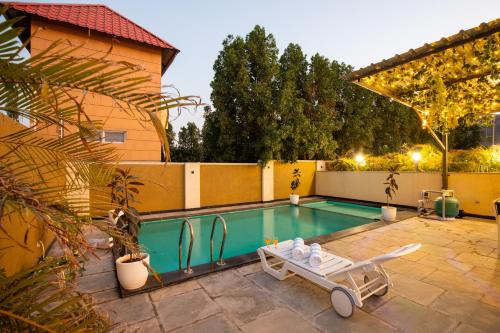 a pool in a backyard with a chaise lounge next to a house at ELIVAAS 2 BHK Pet Friendly Villa with Pvt Pool - Heaven in Hill in Udaipur