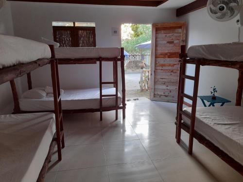 a room with three bunk beds and a doorway at Hostal El Nido del Azulejo in Baru