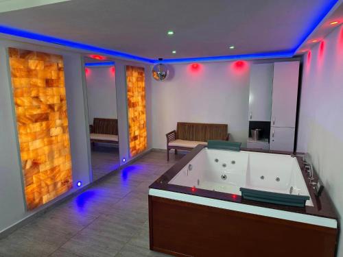 een grote kamer met een bad met paarse verlichting bij Casa Hanea & SPA piscina exterioara incalzita ,sauna, jacuzzi privat in fiecare apartament in Sibiu