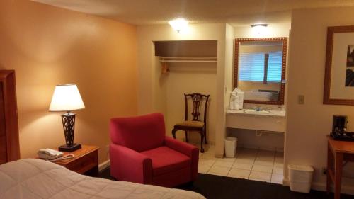 a hotel room with a bed and a chair and a bathroom at Ocean Inn & Suites in Aberdeen