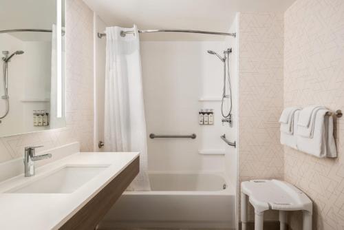a white bathroom with a tub and a sink at Holiday Inn Express & Suites Mobile West I-10 by IHG in Tillmans Corner