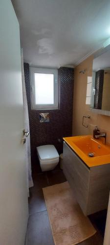 uma casa de banho com um WC, um lavatório e uma janela em Flat in King's George B' Street em Piraeus