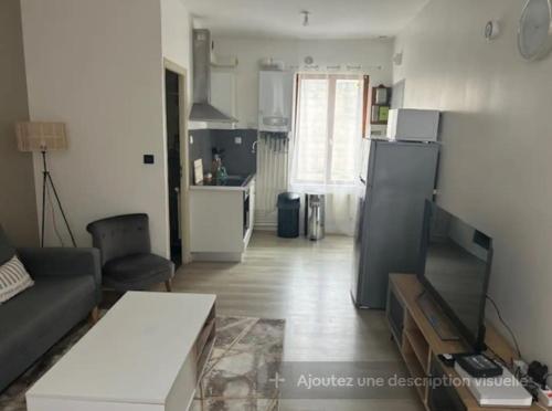 a living room with a couch and a kitchen at Appartement type F2 in Soissons