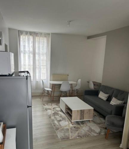 ein Wohnzimmer mit einem Sofa und einem Tisch in der Unterkunft Appartement type F2 in Soissons