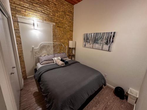 1 dormitorio con cama y pared de ladrillo en Heart of the City: Cozy 2-Bed Loft, en Winnipeg