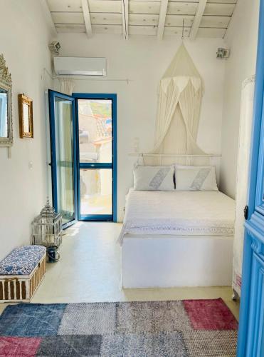 a bedroom with a white bed and a blue door at LemonStello Kythnos in Dhriopís