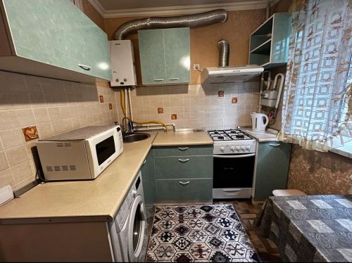 a small kitchen with green cabinets and a microwave at Apartment on Akhmetova 10 in Almaty
