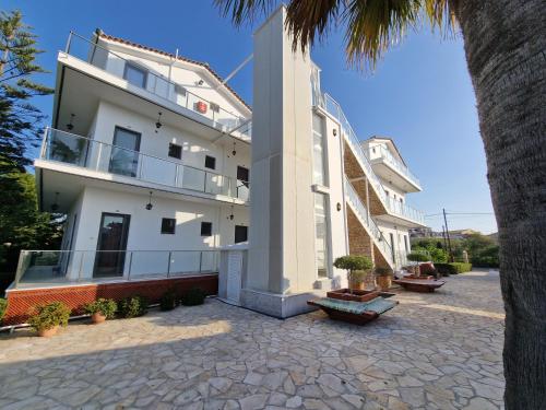 a white building with a balcony and a palm tree at Pettas Apartments in Zakynthos Town