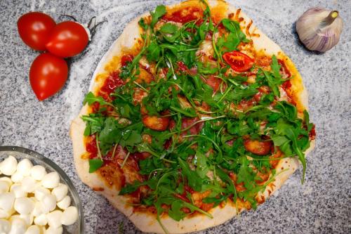 a pizza with greens and tomatoes on a table at Ośrodek BEAVER in Wiele