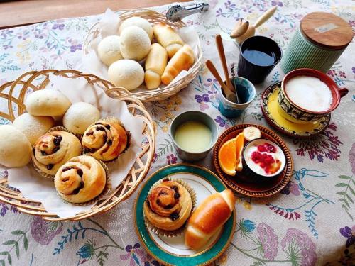 a table with baskets of pastries and bread on it at ペンション 旅とPizzaとお宿 咲色-Sairo- in Nukabira