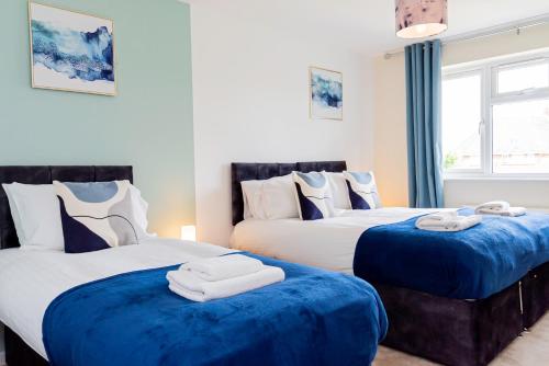 two beds in a room with blue and white at Relaxing 4 Bedroom Retreat For Long Stays Fawley in Totton