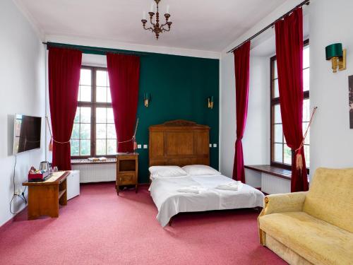 1 dormitorio con cama, sofá y cortinas rojas en Zamek Międzylesie, en Międzylesie