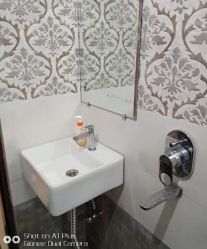 ein Badezimmer mit einem weißen Waschbecken und einem Spiegel in der Unterkunft Hotel City inn in Gaya