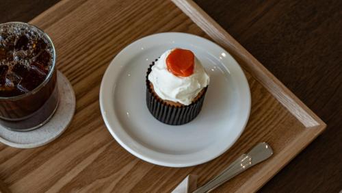 a cupcake on a plate next to a drink at Jimi Stay in Jeju