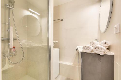 La salle de bains est pourvue d'une douche et de serviettes sur un comptoir. dans l'établissement Domaine de la Gaillarde - maeva Home - Appartement chaleureux avec balcon 3 pièces 4 personnes - Prestige - super Home MAE-9791, à Roquebrune-sur Argens