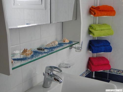 uma casa de banho com toalhas numa prateleira por cima de um lavatório em Kleo Joannas Apartments em Ermioni