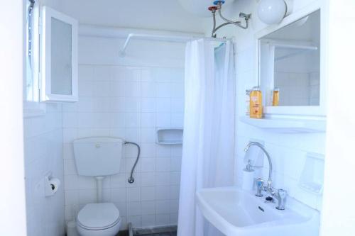 a white bathroom with a toilet and a sink at Ioanna's House@Foinikas Syros in Finikas