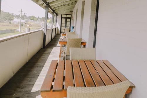 a porch with a wooden bench and chairs at Royal Hotel Capertee in Capertee