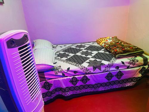 Habitación púrpura con cama y ventilador en Coorg Green Moon, en Madikeri