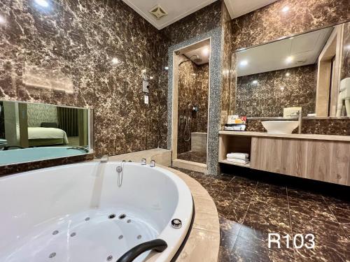 a large bathroom with a tub and a sink at Cigar Motel in Tainan