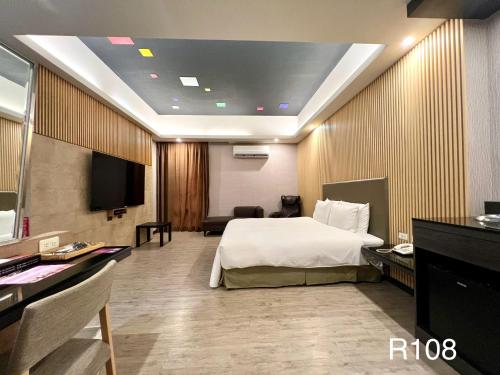 a hotel room with a bed and a flat screen tv at Cigar Motel in Tainan