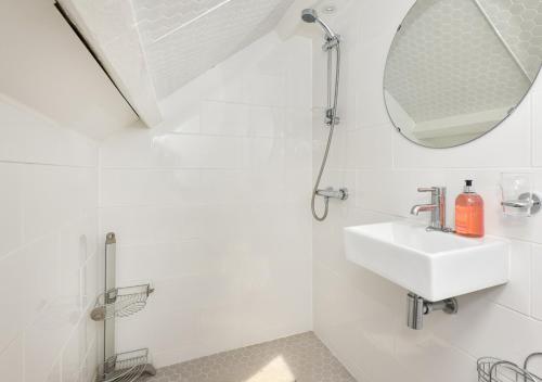 La salle de bains blanche est pourvue d'un lavabo et d'un miroir. dans l'établissement Mur Llwyd, à Bottwnog