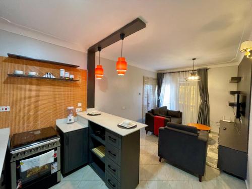 a kitchen with a counter and a living room at Athena Apartments in Kampala