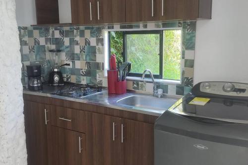 um balcão de cozinha com um lavatório e uma janela em Campo Alegre: Loft con Vista em Medellín