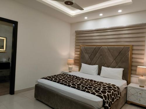Schlafzimmer mit einem großen Bett mit einem Kopfteil aus Holz in der Unterkunft Designer 2BHK, PIMS Facing in Elysium in Islamabad